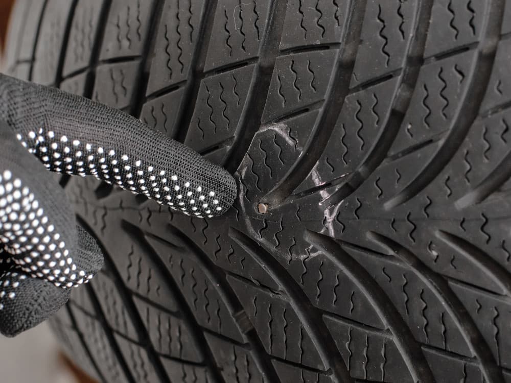 Glove pointing at tyre puncture